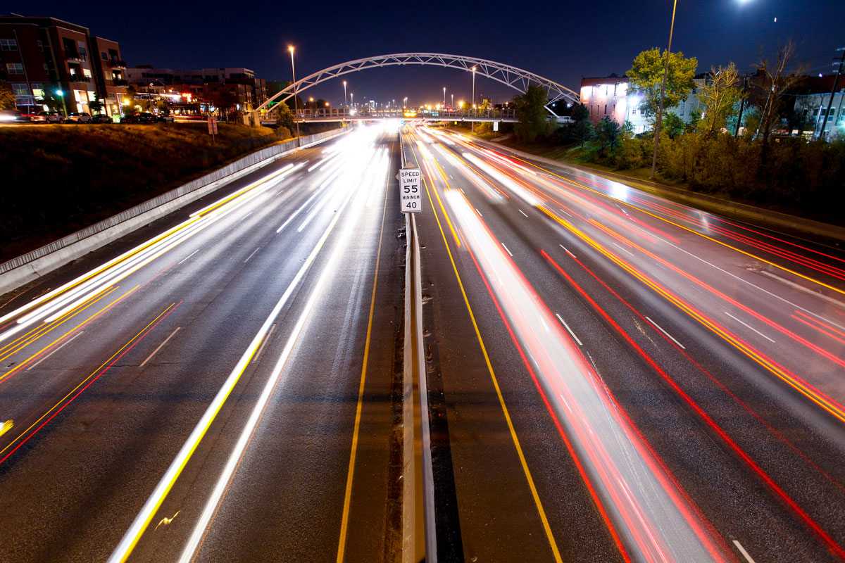 Aerial view of I-25 in Denver at night. Car headlights are blurred in a long exposure image.